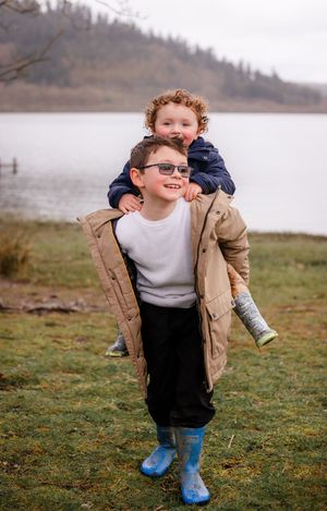 Older sibling carrying younger on back sibling portrait session family photography near you