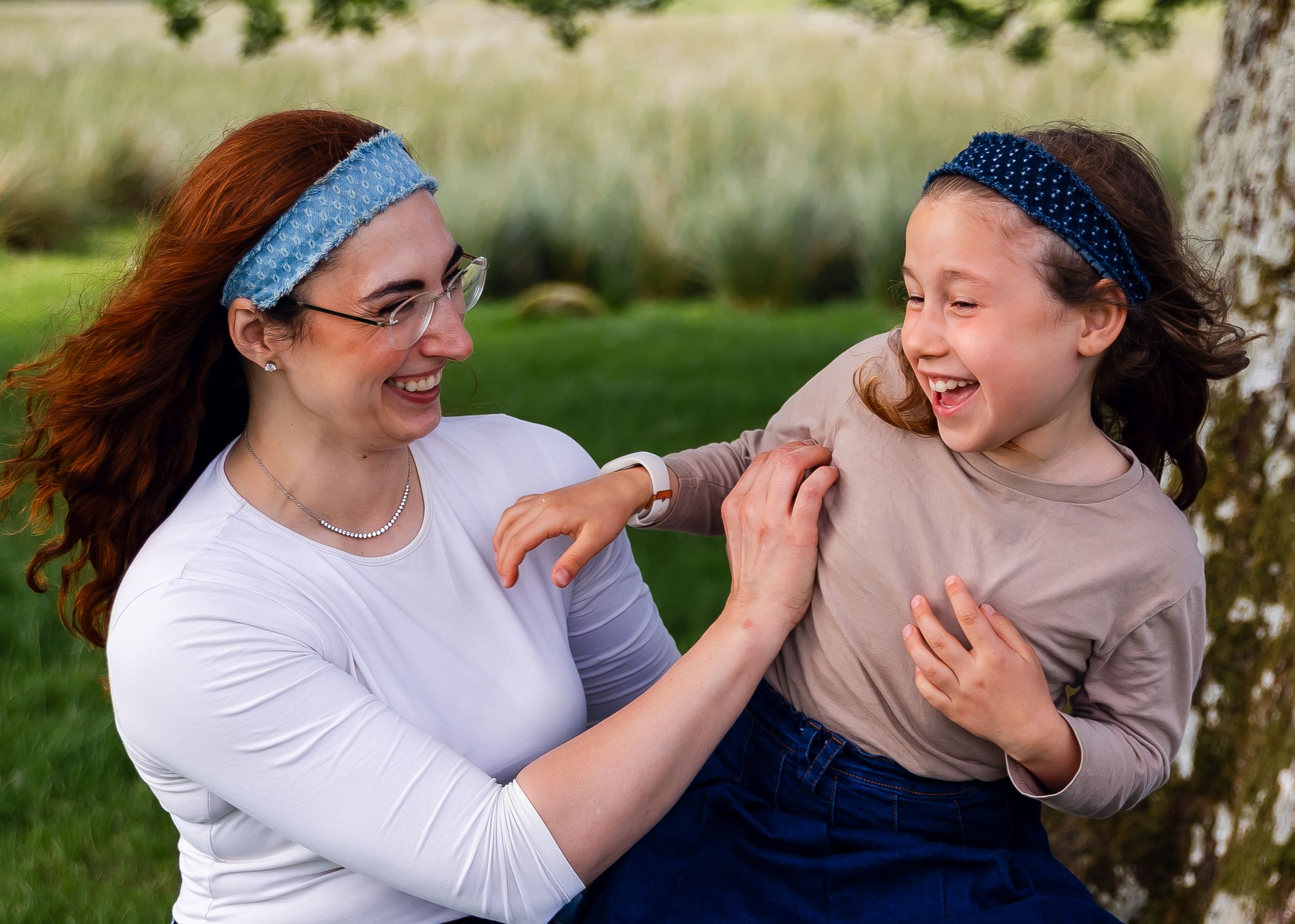 A mother and daughter laughing together in a grassy field family connection family photographer near you