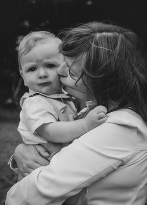 Mother cuddling a baby. Close up family photography, tender parent child moment.