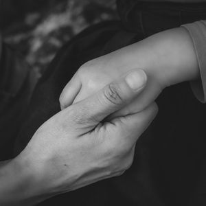 Close up of adult and child holding hands. Emotional family photography parent child connection