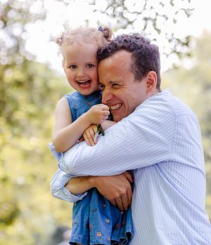 Father hugging daughter while smiling. Emotive family photography, father daughter photoshoot