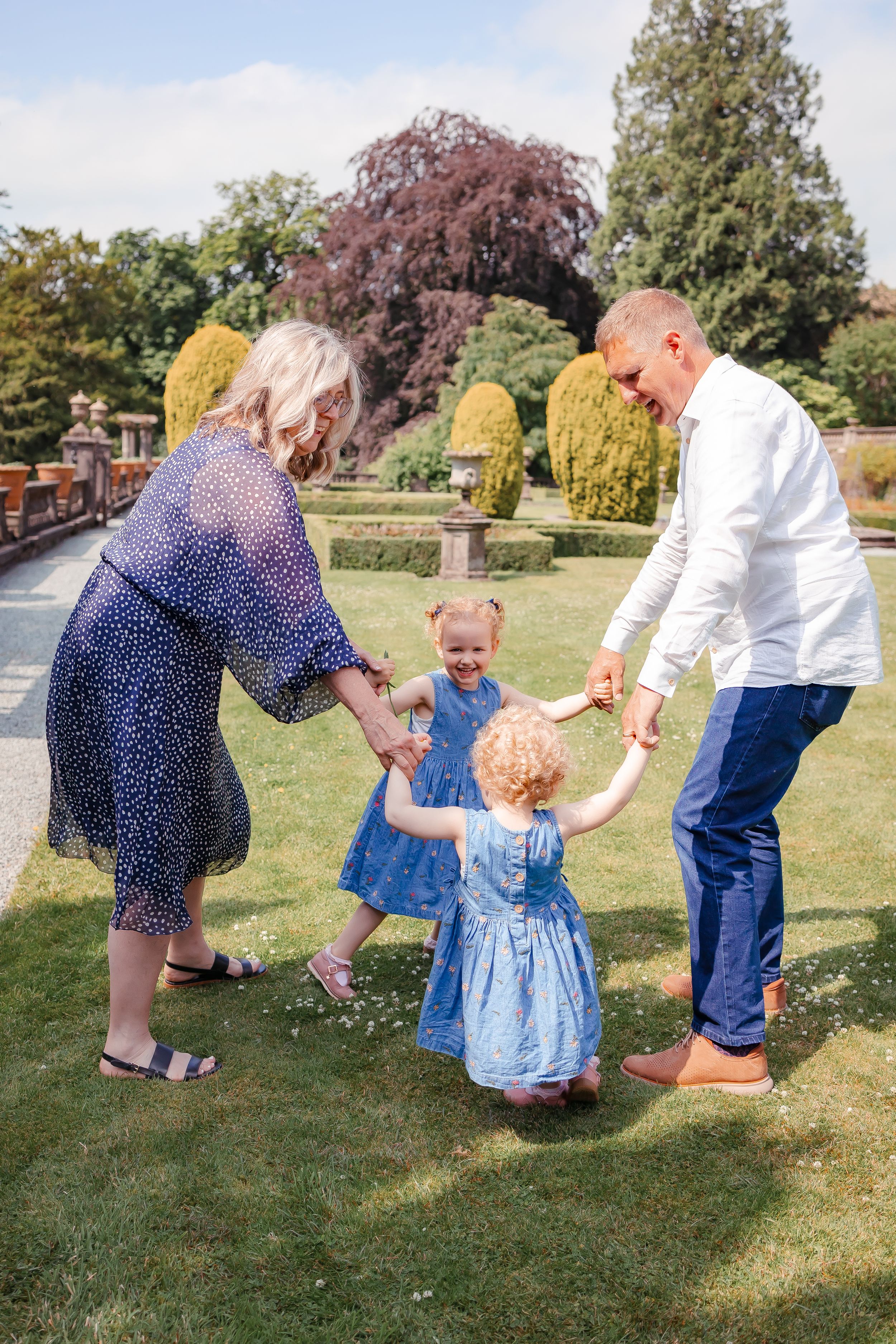 Grandparents holding hands with children in a garden Multigenerational family photoshoot