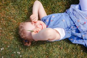 Girl lying in the grass smiling. Playful family photography lifestyle photoshoot