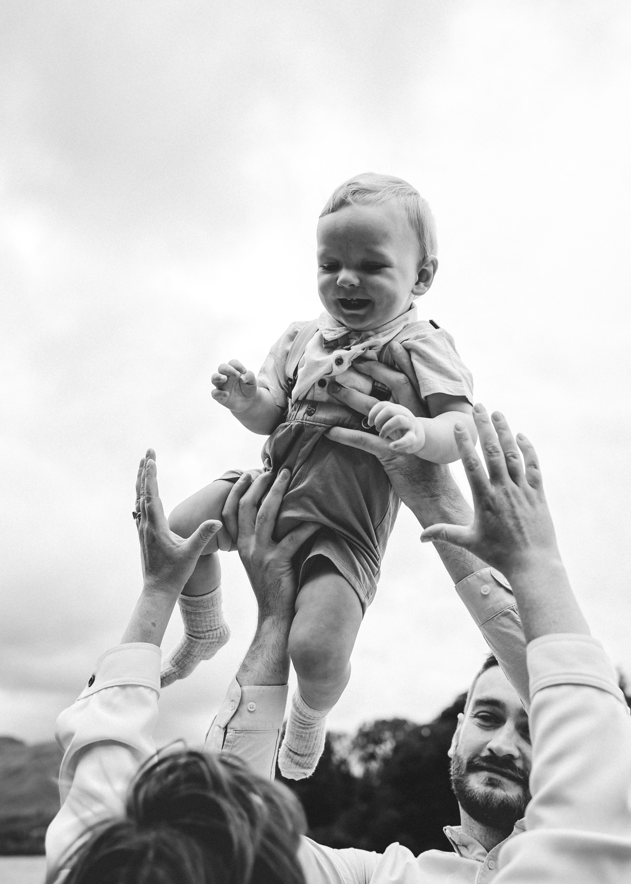 Black and white image of a baby being lifted in the air timeless family photography joyful family moment