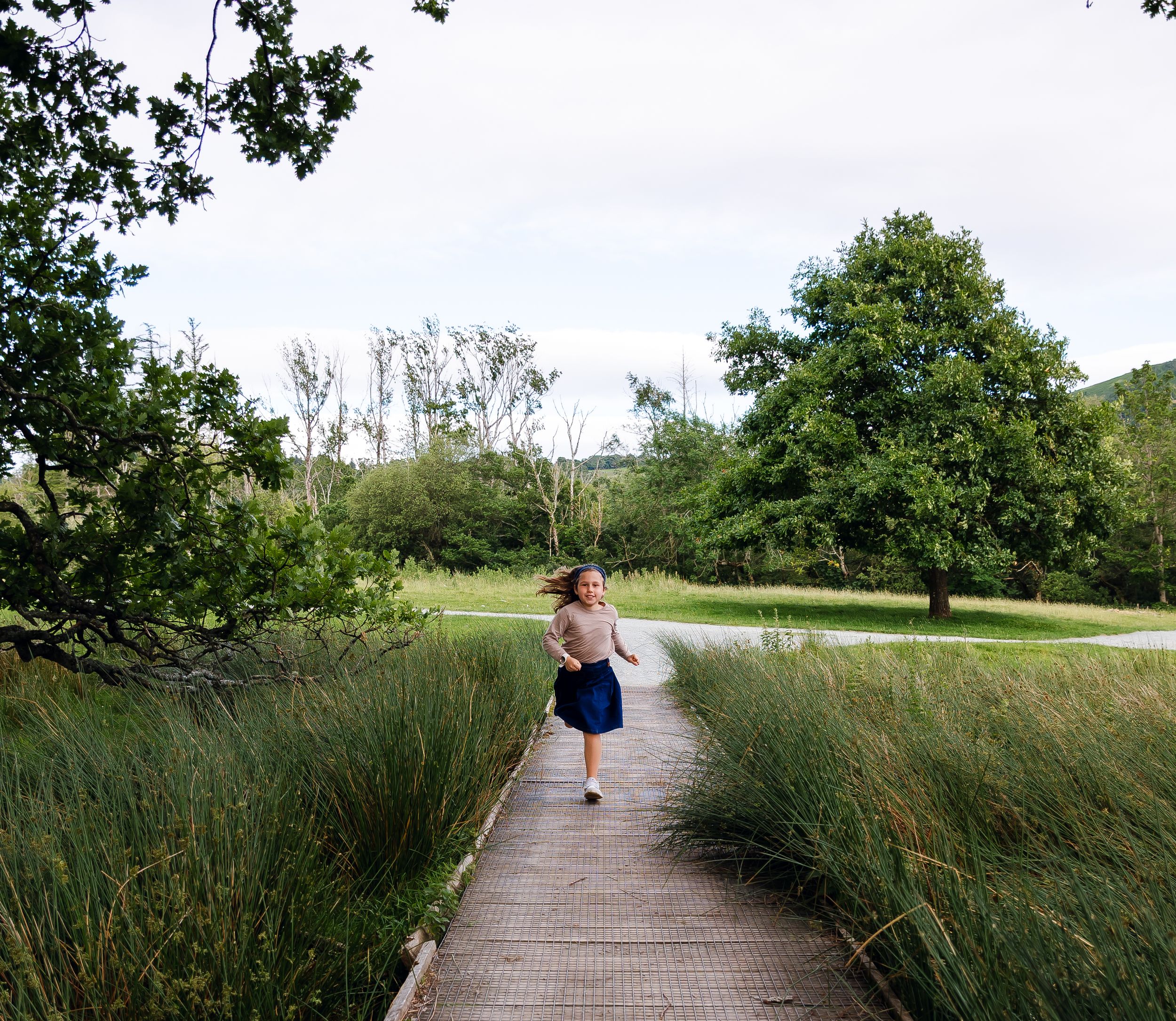 Child running down boardwalk in a nature reserve. adventure family photography lifestyle session.
