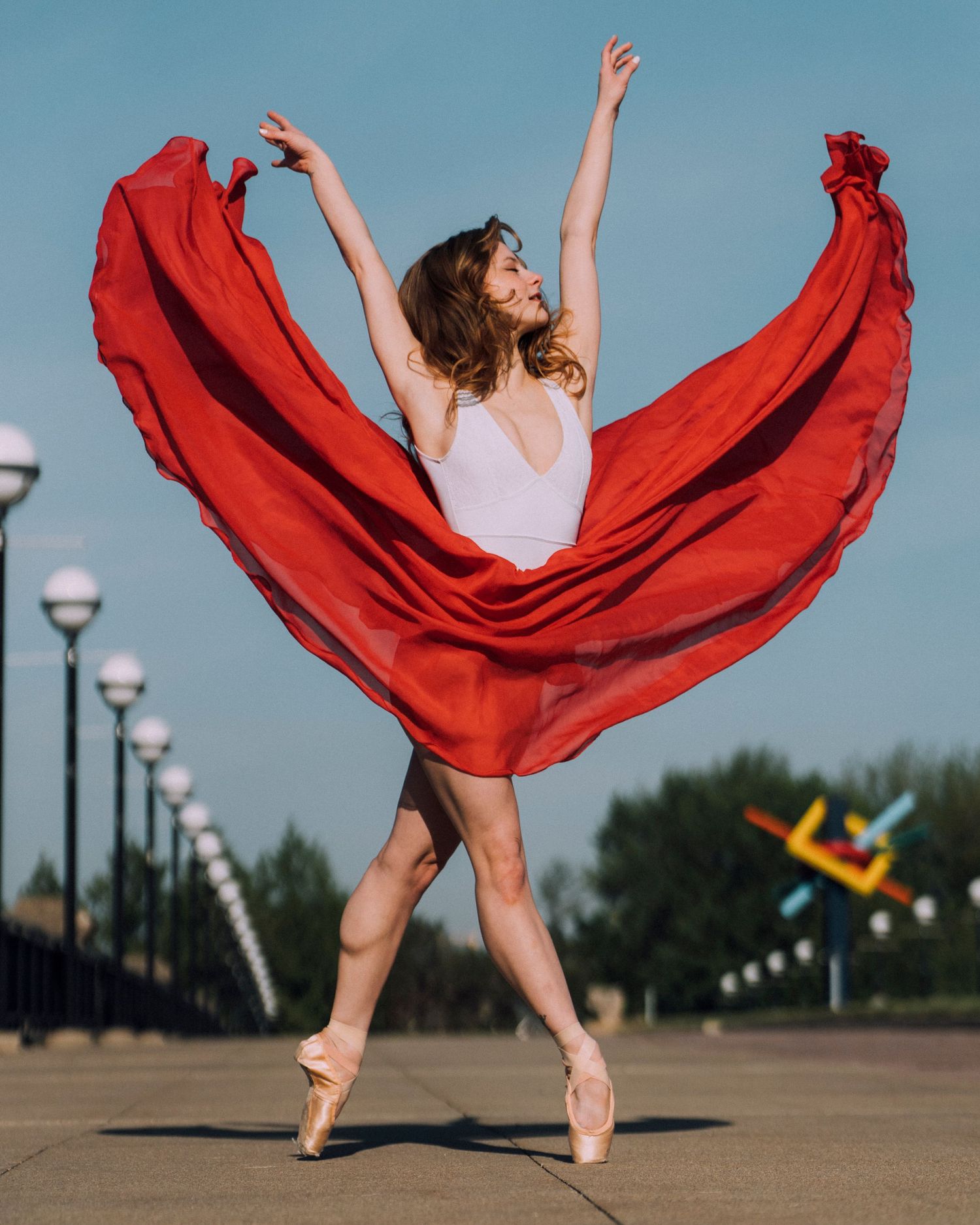 Petite Indy Ballet dancer wearing a red maxi skirt posing at sunrise for indy ballet photography session in White River State Park,