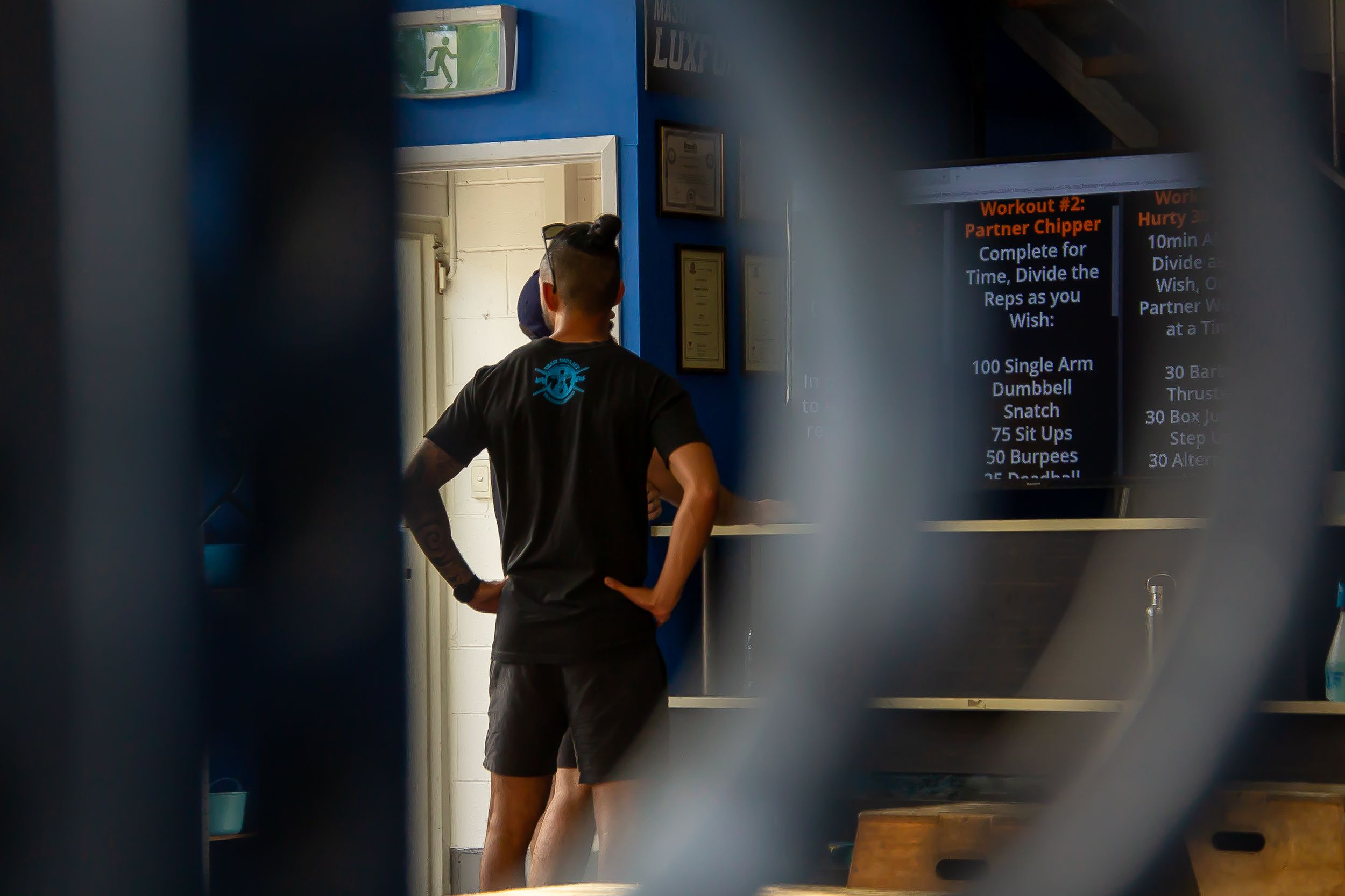 Silhouette of someone standing in a dimly lit gym or fitness space.