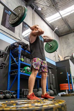 Low angle view of someone performing kettlebell exercises in a gym with blue storage racks.