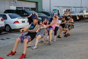 Group fitness class performing squat exercises outdoors in parking lot.