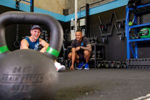 Athletes resting near large kettlebells in a functional fitness gym setting.