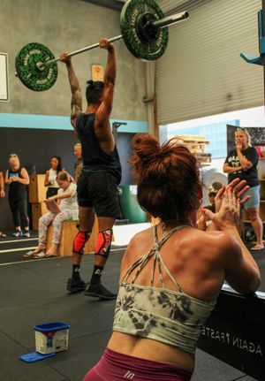 Group workout session with participants doing overhead ball exercises in a gym.