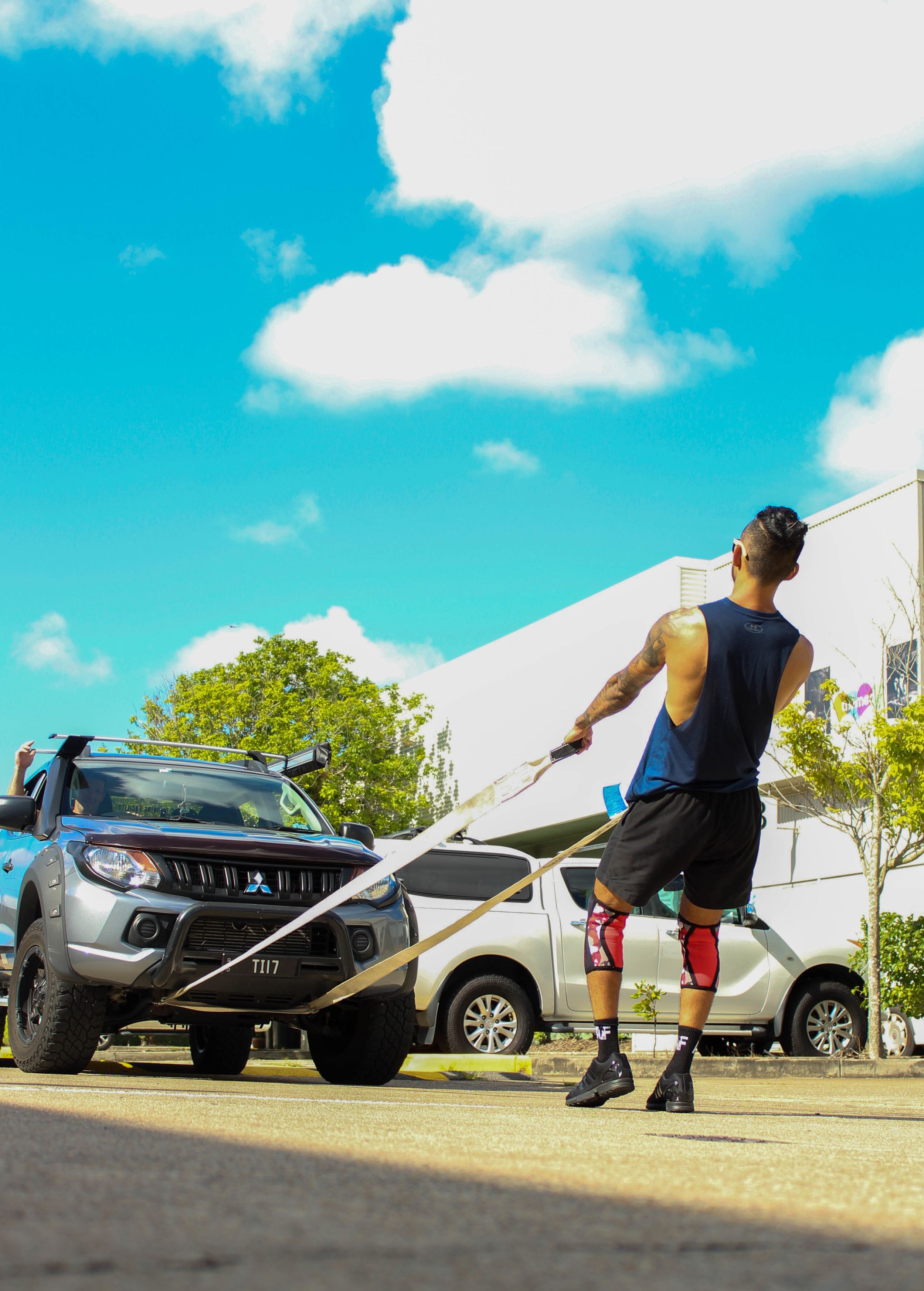 Person demonstrating burpee exercises in a parking lot on a sunny day.