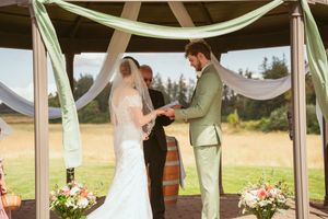 Elegant wooden gazebo adorned with mint green and white drapery for an outdoor wedding ceremony.