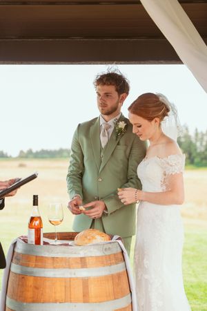 A couple performs a wine ceremony together using a wooden barrel at a rustic wedding reception.