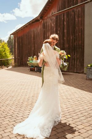 A flowing white wedding dress spins gracefully against a rustic red barn backdrop on a sunny afternoon.