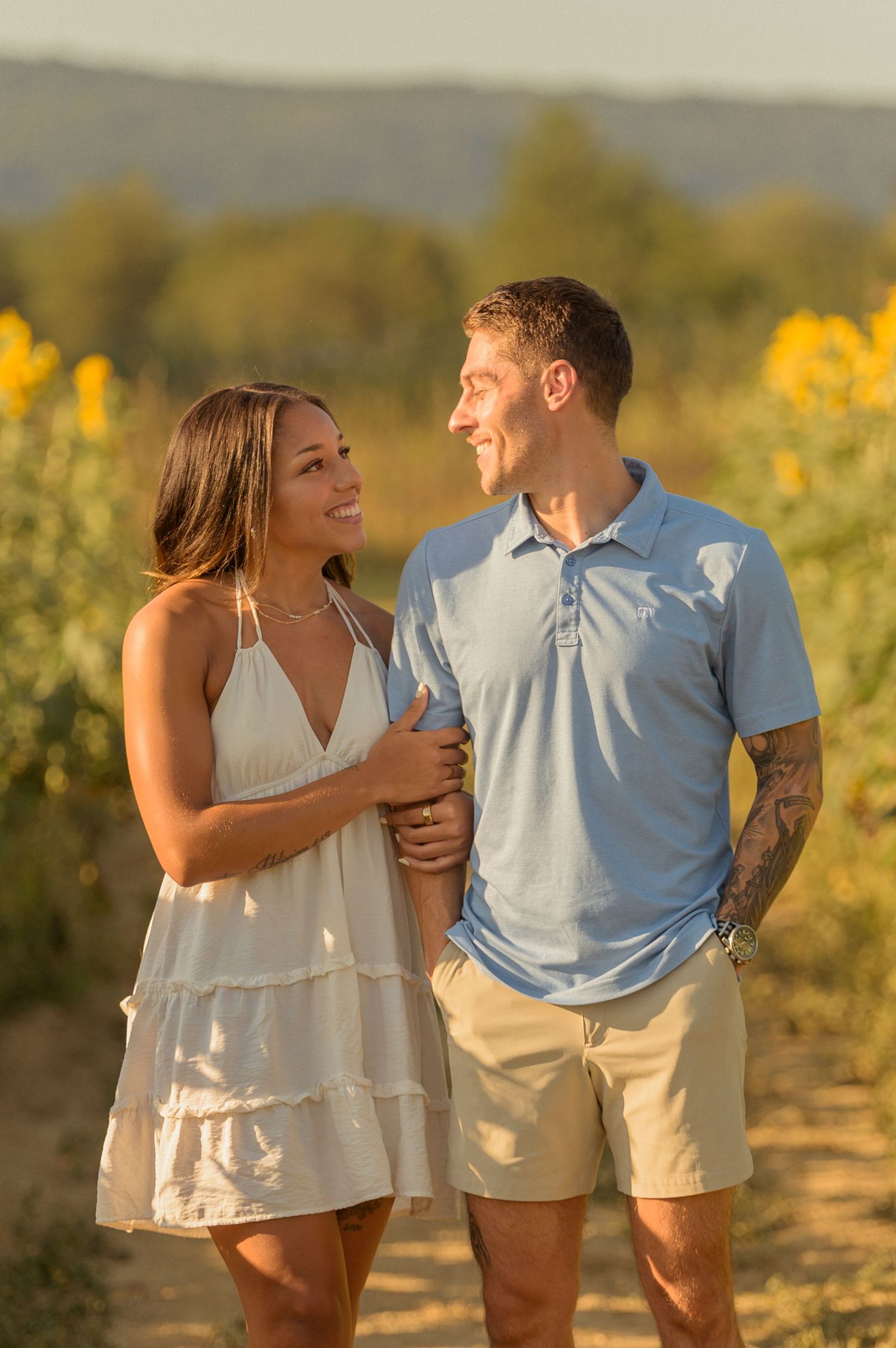 A couple sharing a happy moment while leaning on a wooden dock railing surrounded by trees.