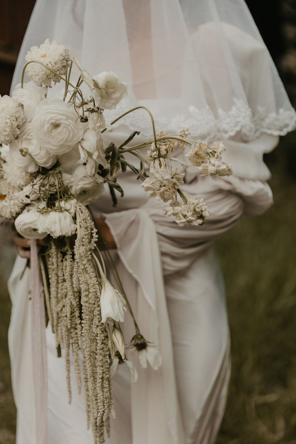 Elegant white floral bouquets with cascading elements held by wedding party.