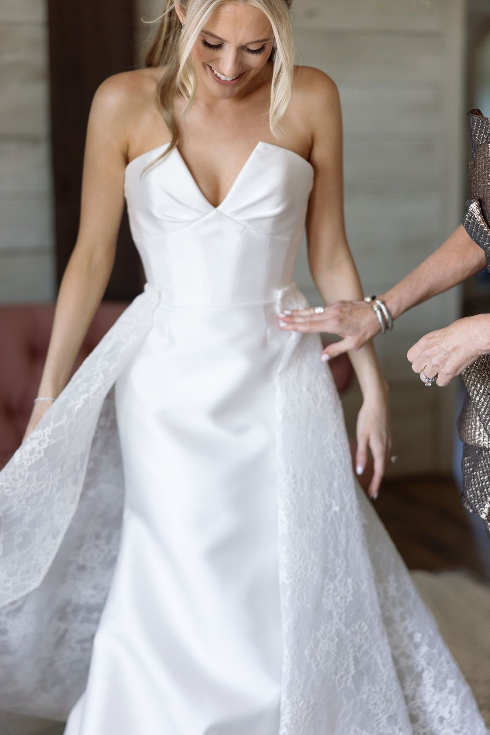 Close-up detail shots of a white wedding dress with delicate lace details and fitted bodice during a bridal fitting.