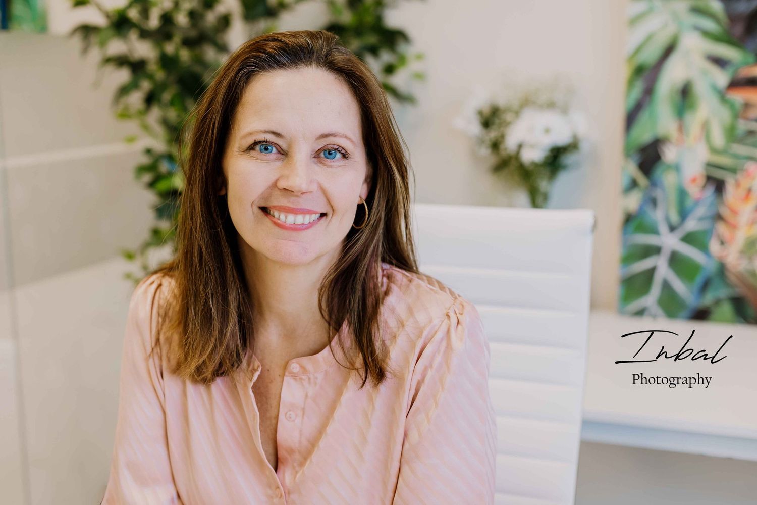 portrait of a businesswoman wearing a soft pink shirt sits confidently, looking directly at the camera.