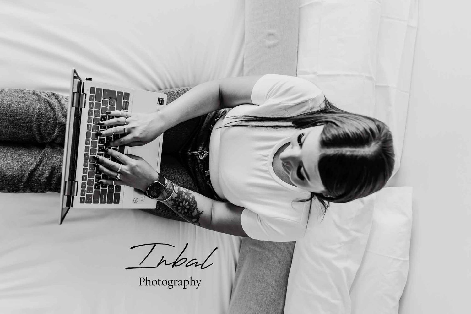 Overhead shot of a woman working on a laptop on a bed, showcasing a relaxed and professional personal branding session.