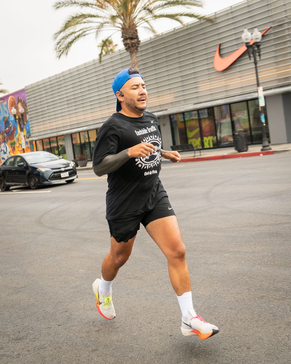 A runner in athletic gear jogging down a palm-lined city street during a race.