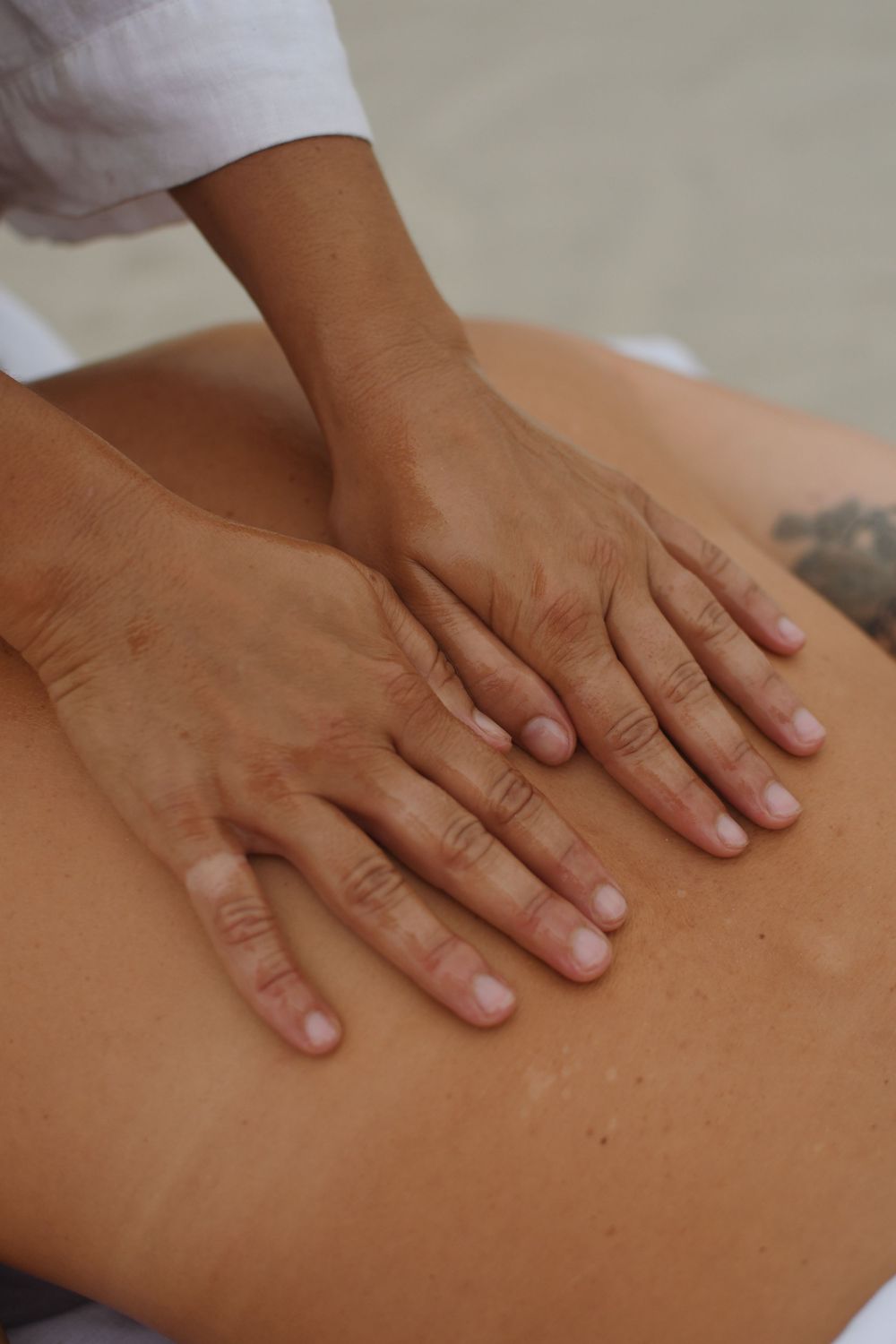Close-up of hands performing therapeutic massage techniques on a person's back during a spa treatment session.