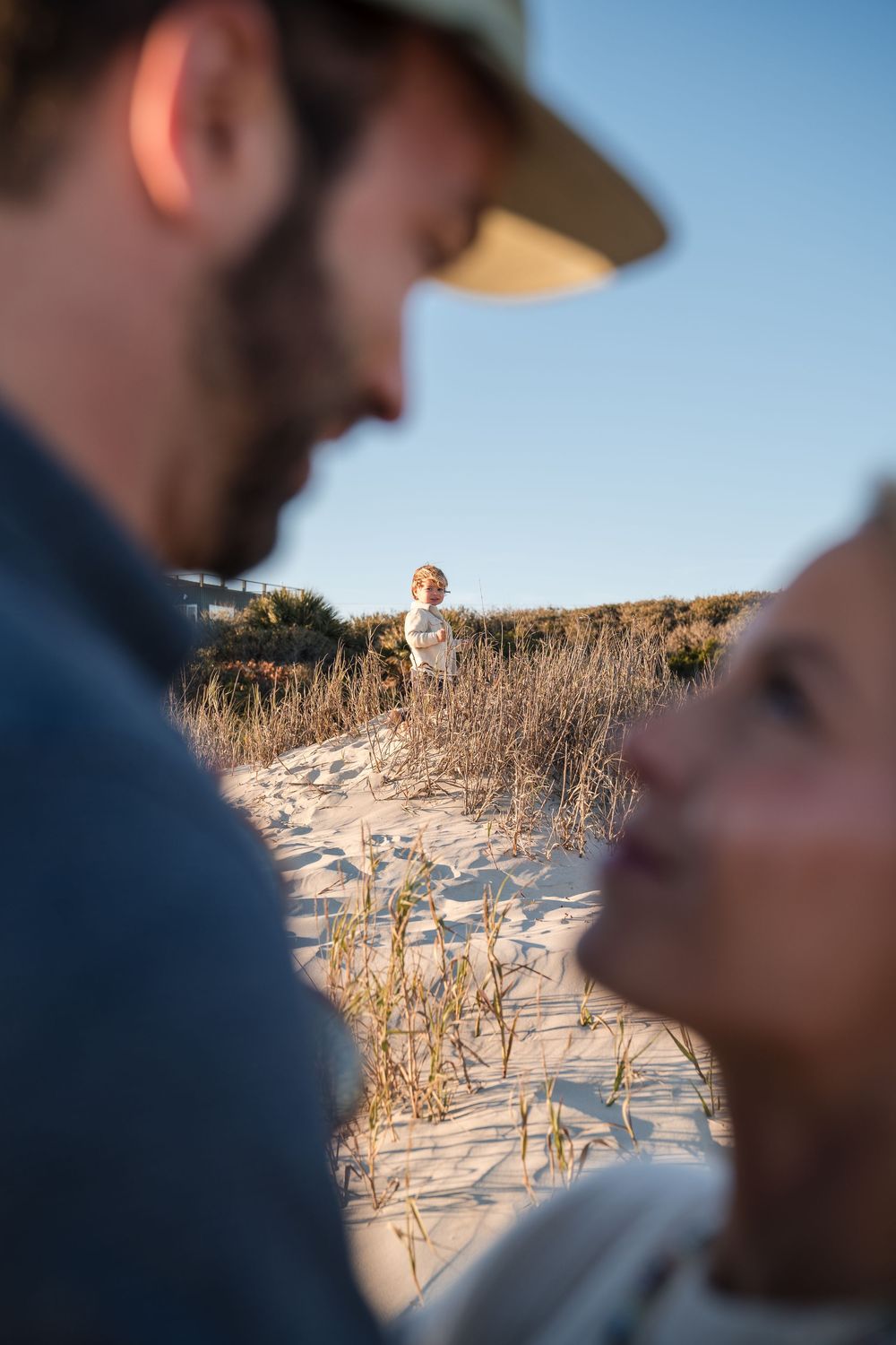 Family enjoying a scenic beach path through sand dunes at sunset.