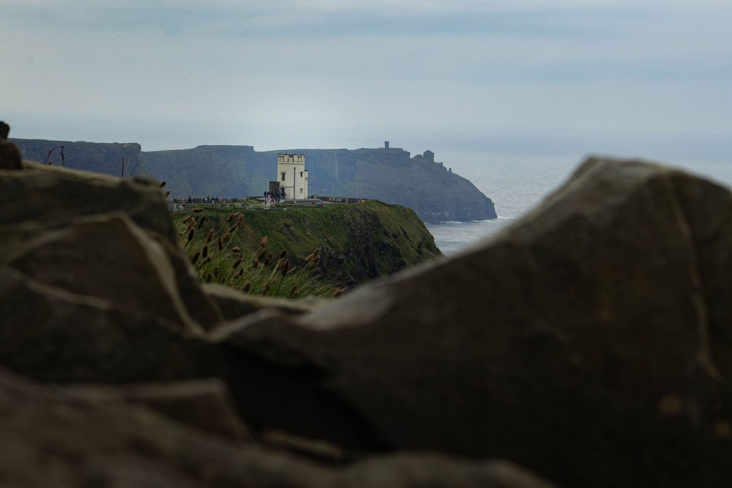 Majestic coastal cliffs rise from the ocean below with green grass-covered slopes stretching to the horizon.