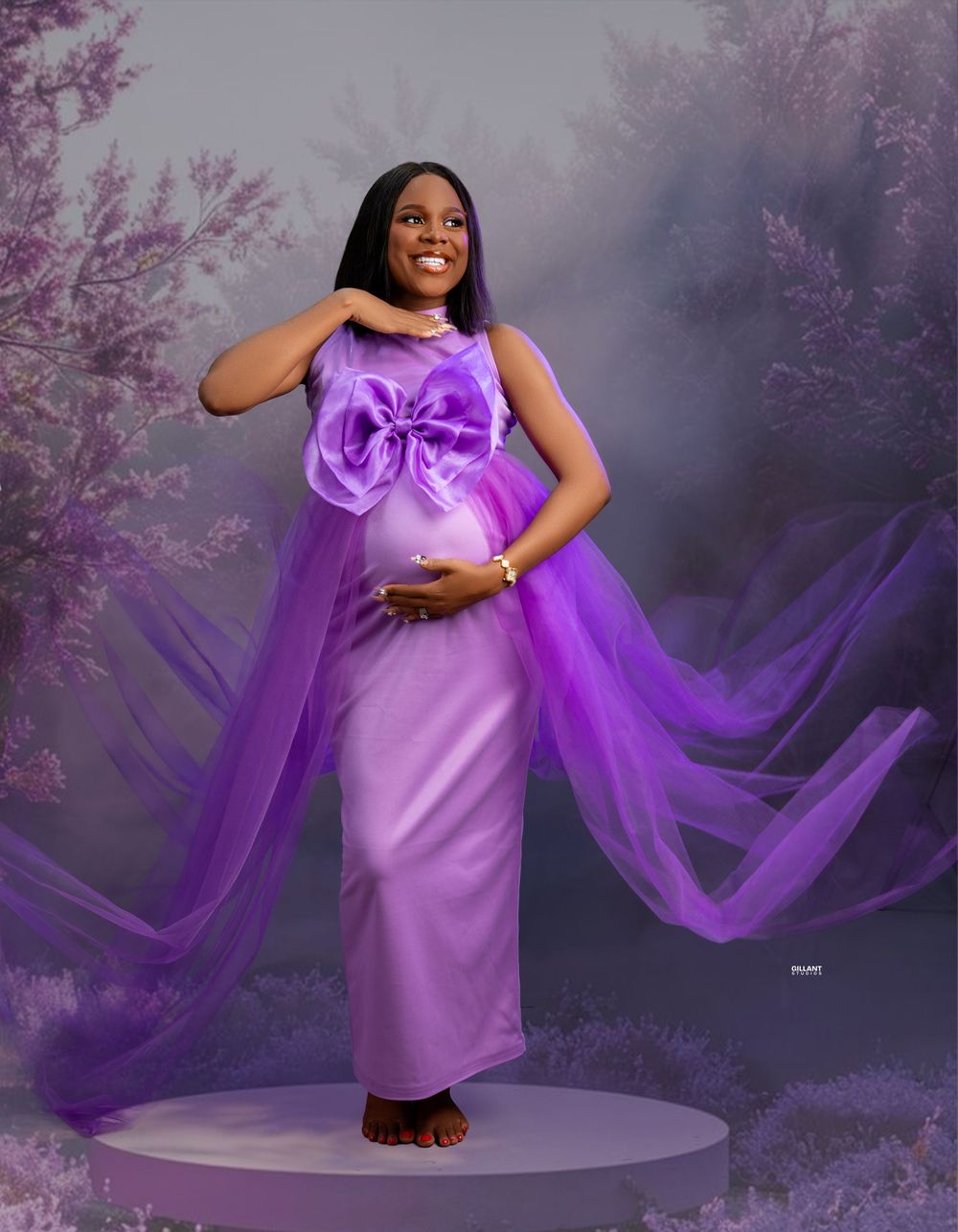 Elegant maternity photo featuring purple gown with bow detail and flowing cape in misty backdrop.
