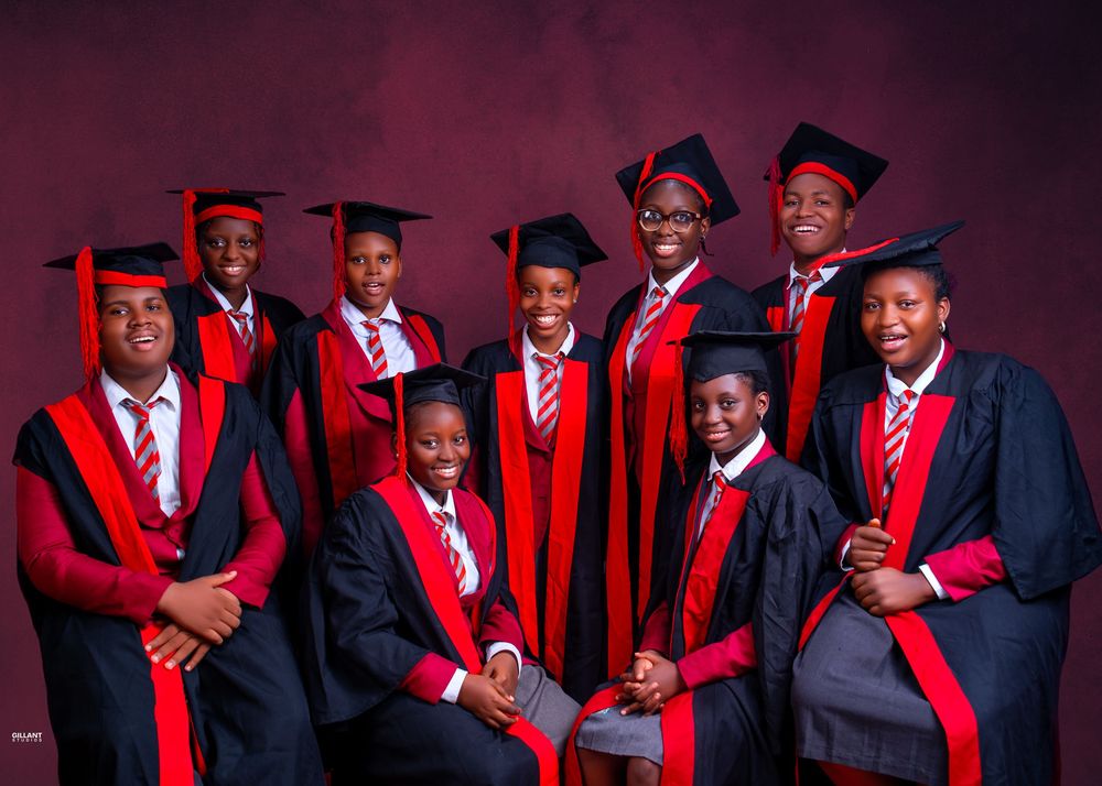 Group graduation photo of students in matching red and black academic regalia.