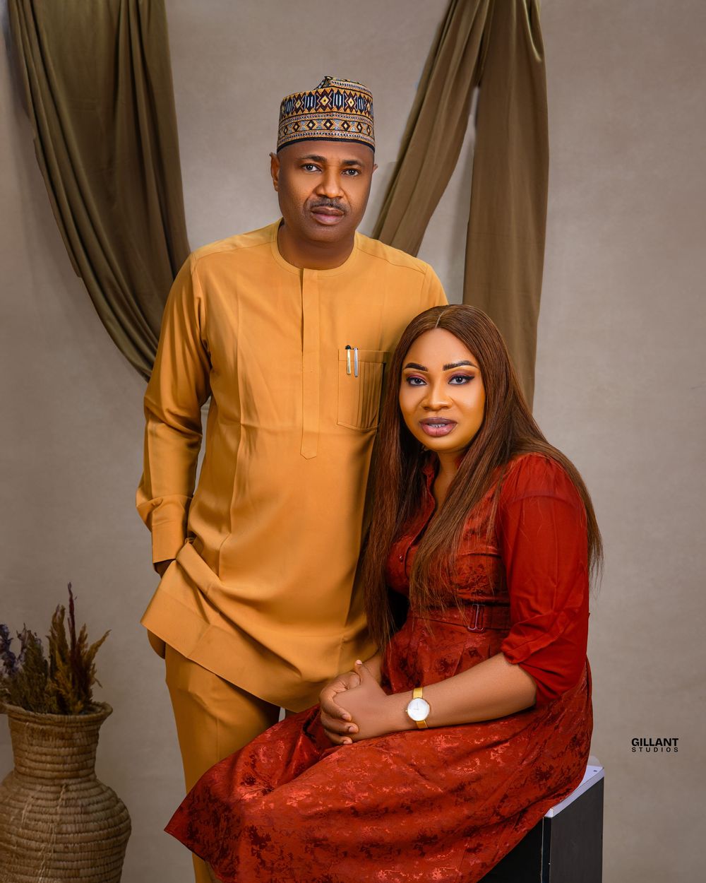 Studio portrait session featuring traditional African formal wear in mustard yellow and burgundy.
