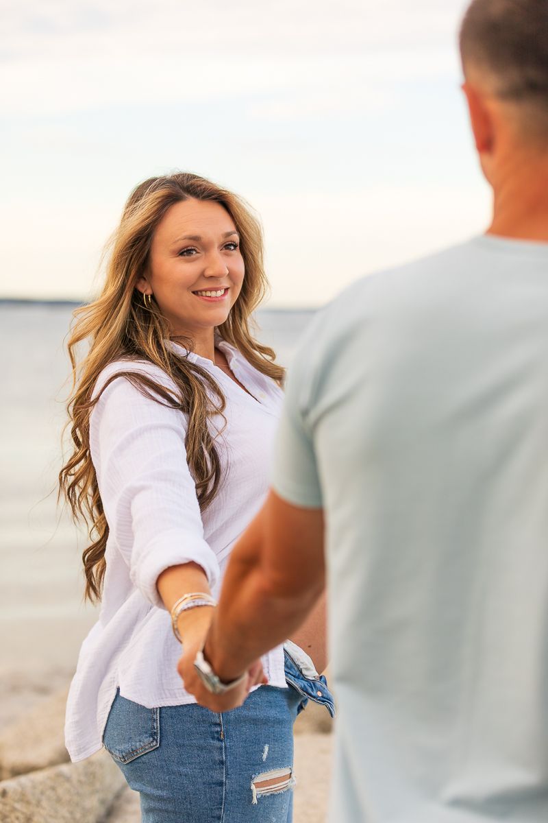 A couple dances together on a beach at sunset wearing casual clothing.