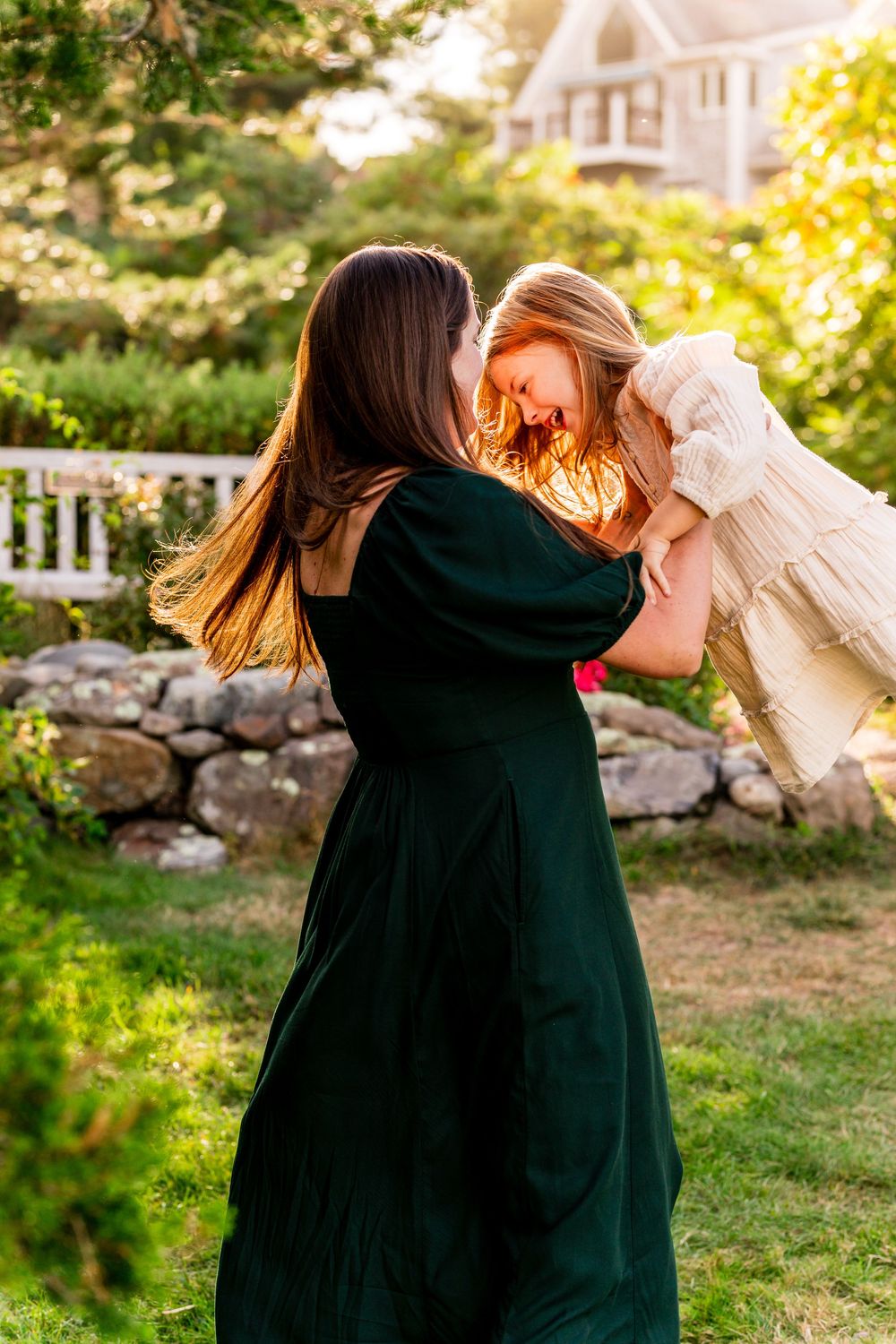 Candid family embraces and interactions photographed in a garden with stone wall backdrop.