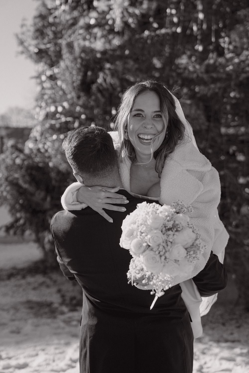A happy couple embracing and laughing in a black and white outdoor wedding photo series.