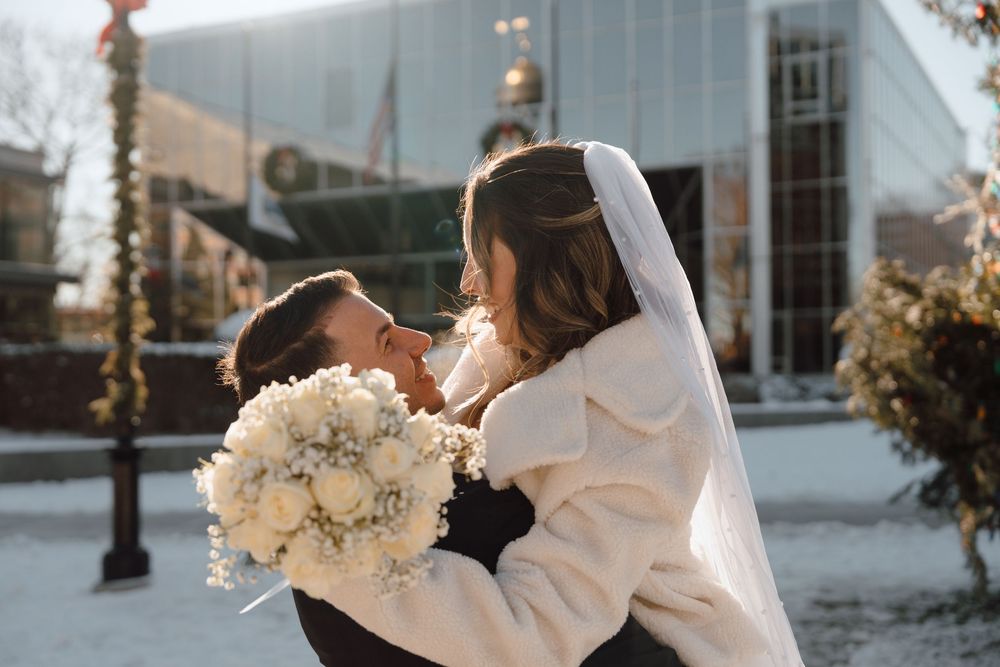 A couple shares a romantic moment on their winter wedding day with white bouquet and long flowing veil.