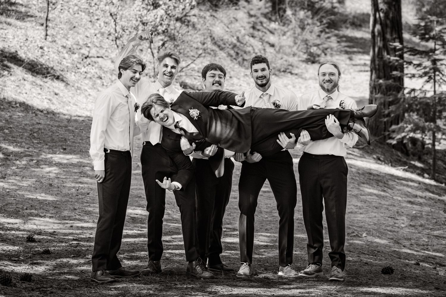 Black and white photo of groomsmen posing casually outdoors.