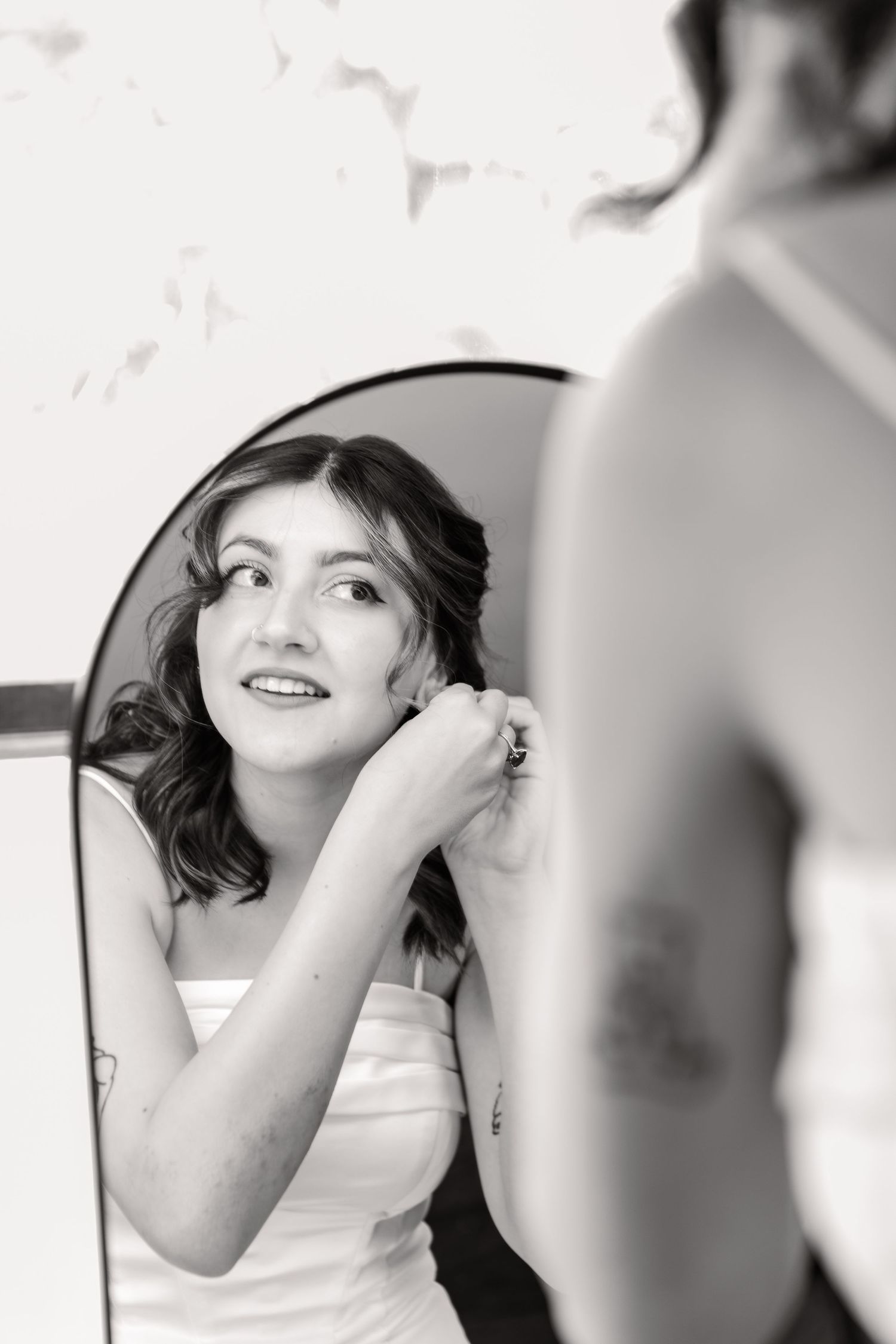 Black and white portrait of someone putting on earrings while getting ready for a special occasion.