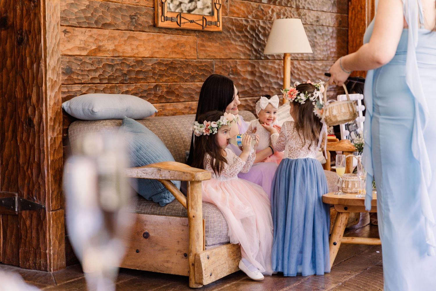 Wedding party members in pastel blue dresses preparing in a rustic wooden interior.