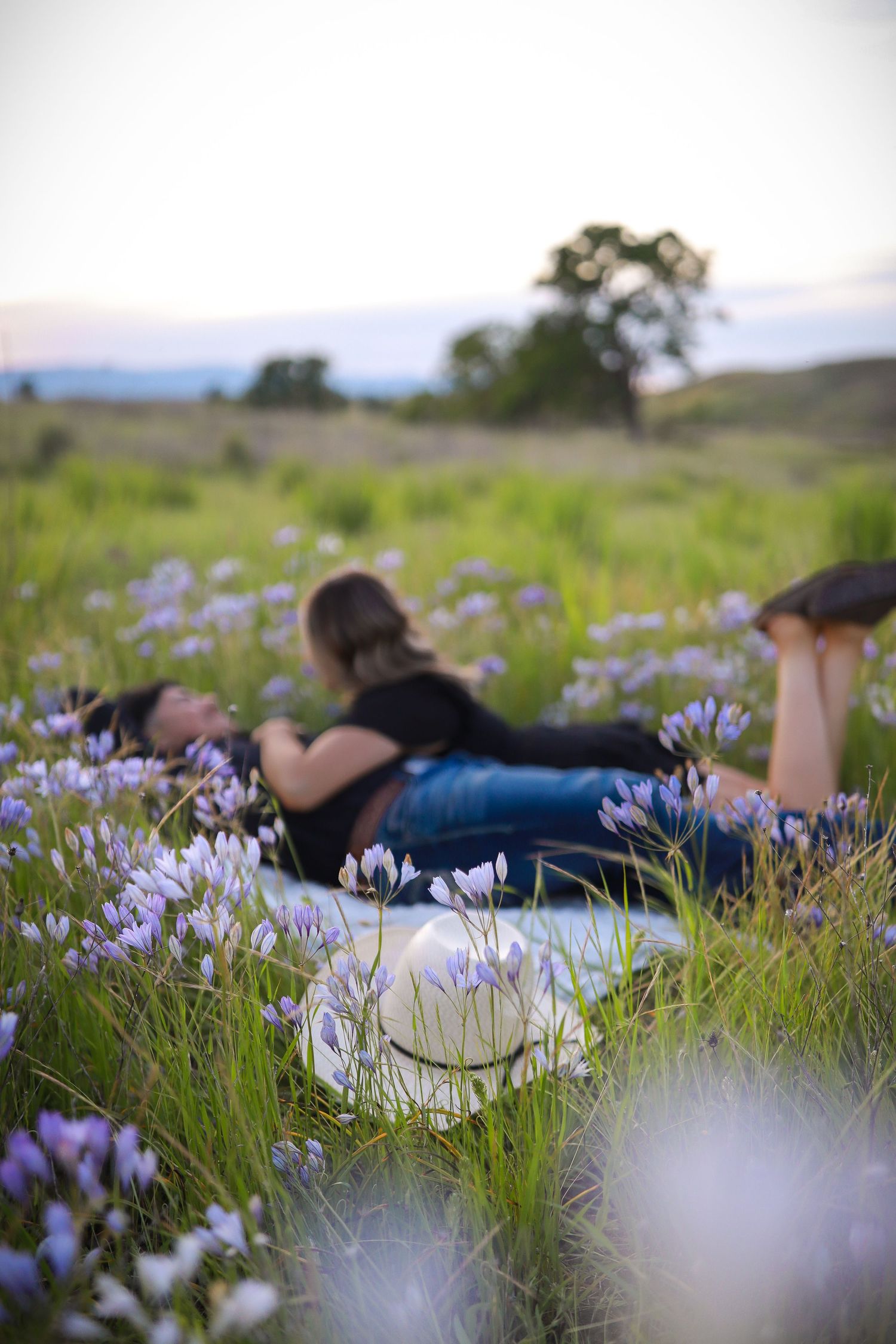 Couple lying in a field of purple wildflowers during a dreamy outdoor photo session.