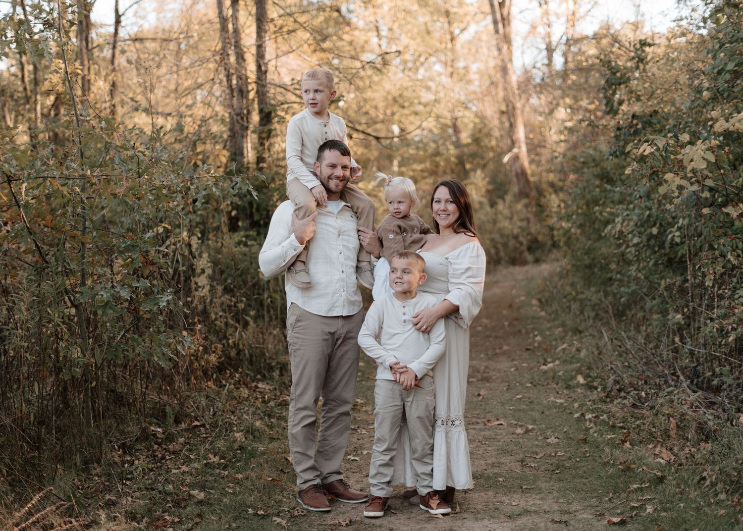 Family of four posing together on forest path during autumn photo session.
