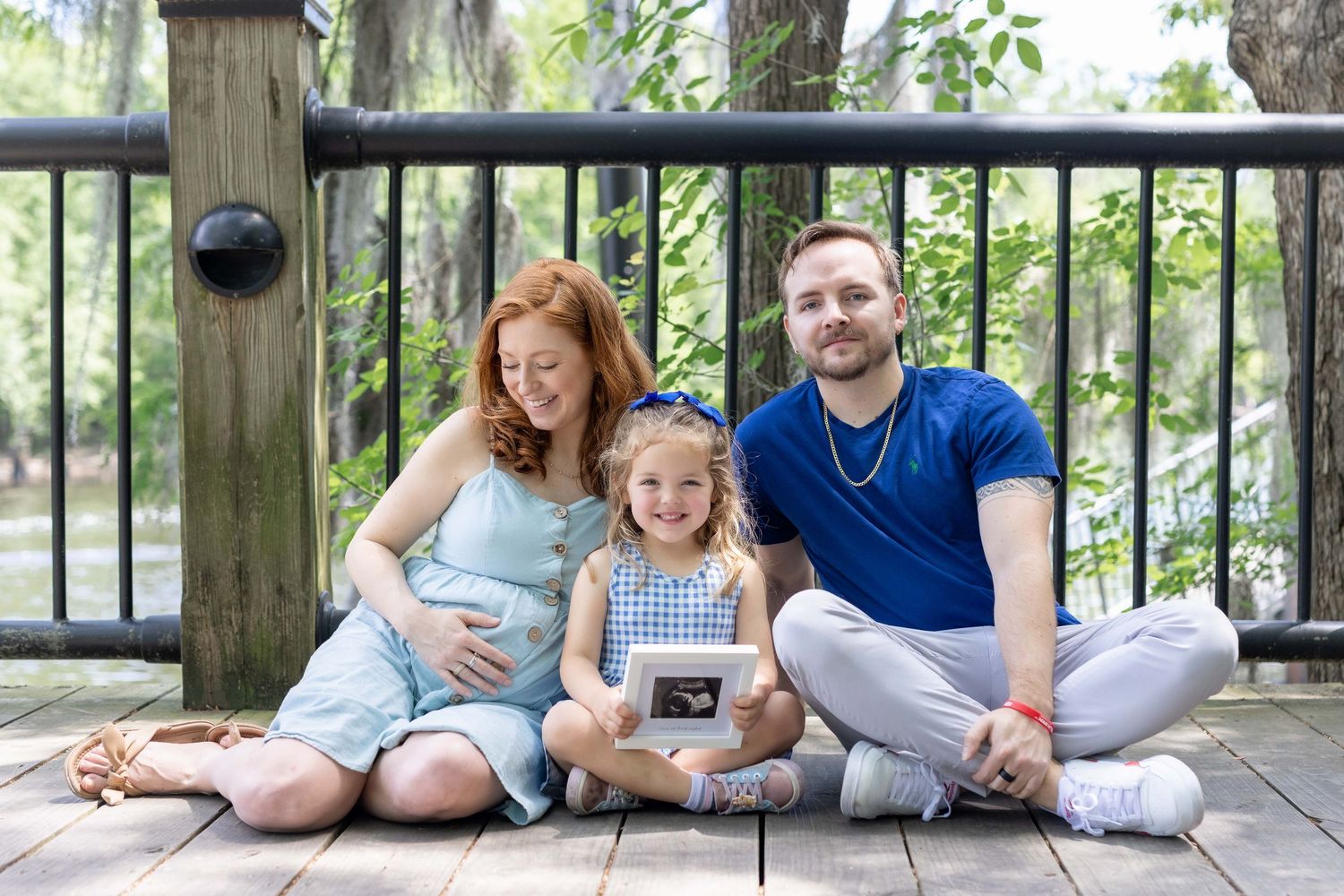 Maternity photo of pregnant woman with husband and daughter, sitting together in a loving family pose, Amherstburg Ontario.