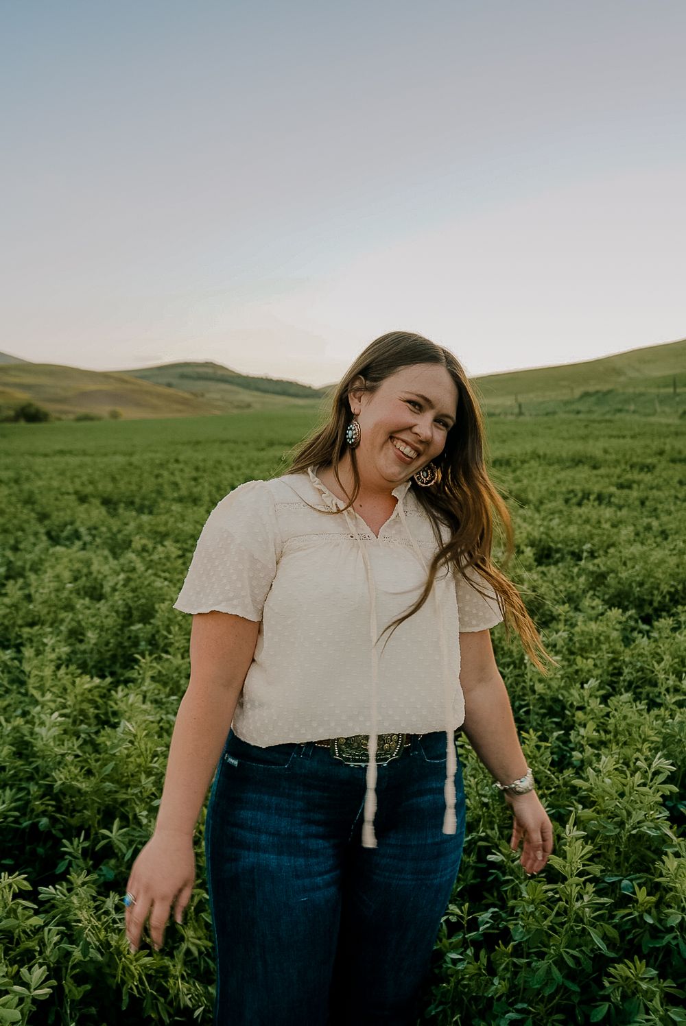 A young woman being carefree in a alfalfa field while smiling