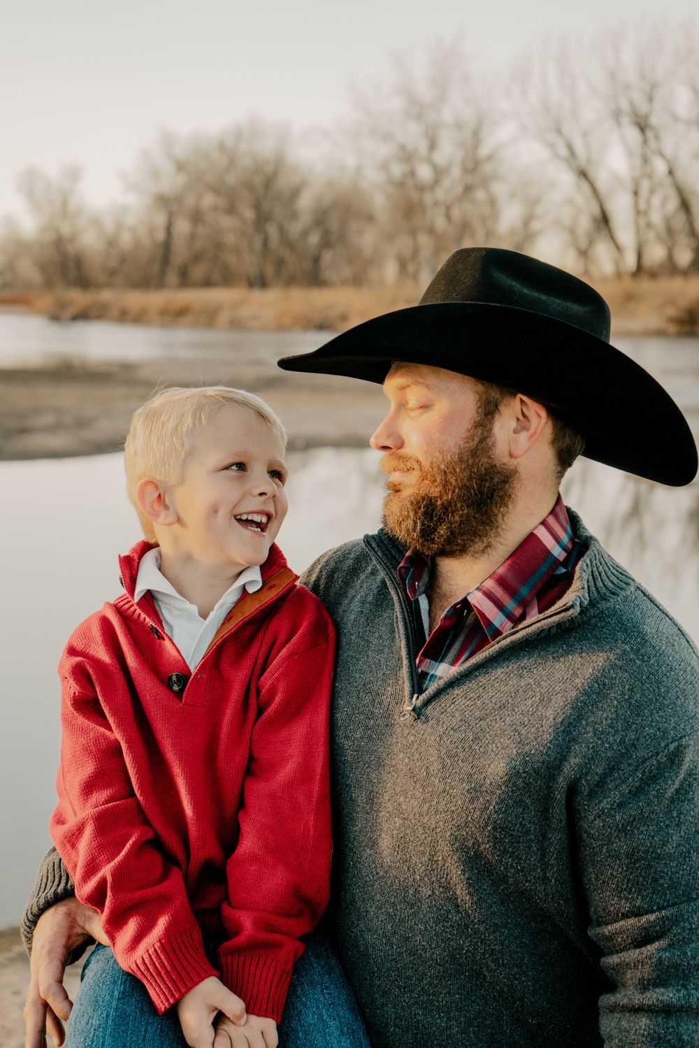 A father and son laughing at one another with a river in the background