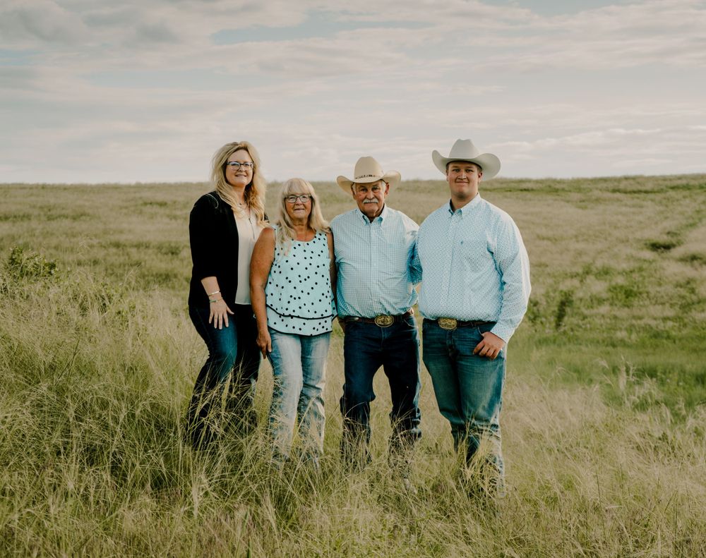 A family of four smiling at the camera in a grassy plain