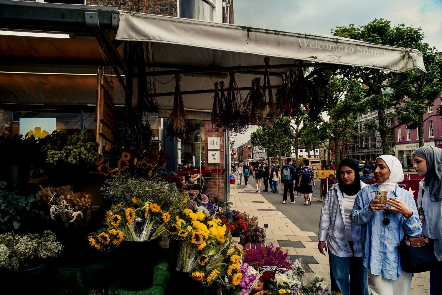 Flower market stall with bright yellow sunflowers on display in an urban shopping area.
