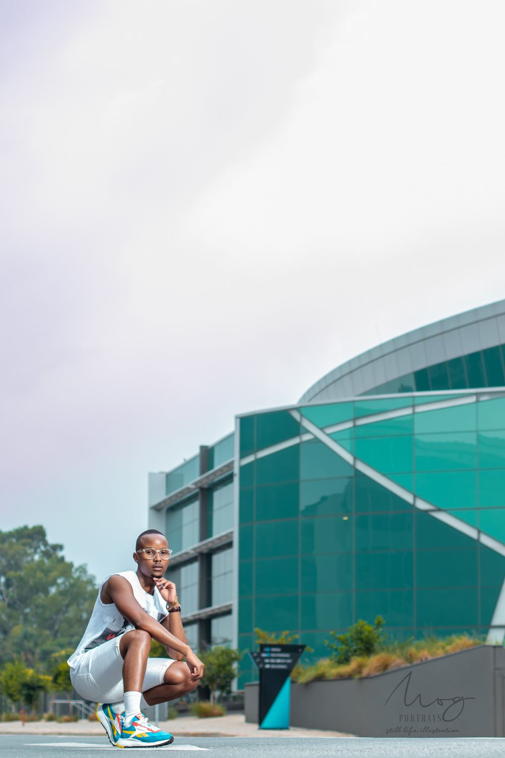 Athletic figure crouches near modern teal building architecture.