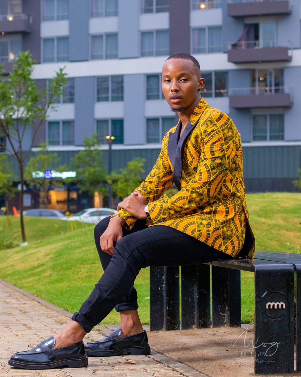 Fashion portrait featuring yellow patterned jacket against modern building backdrop.