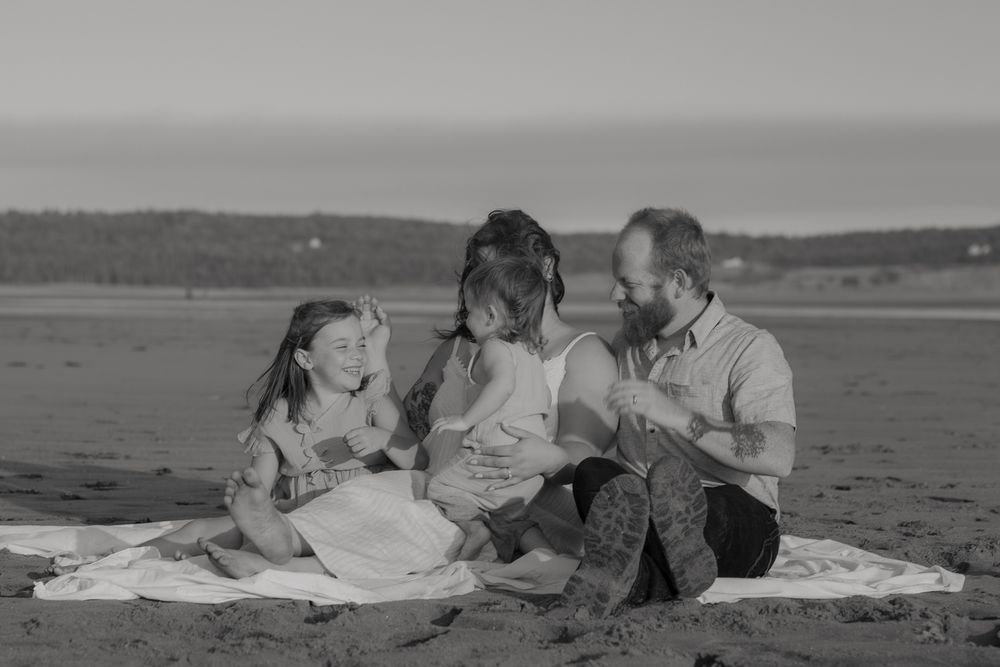 A black and white photo series shows a couple lounging and relaxing together on a beach blanket.