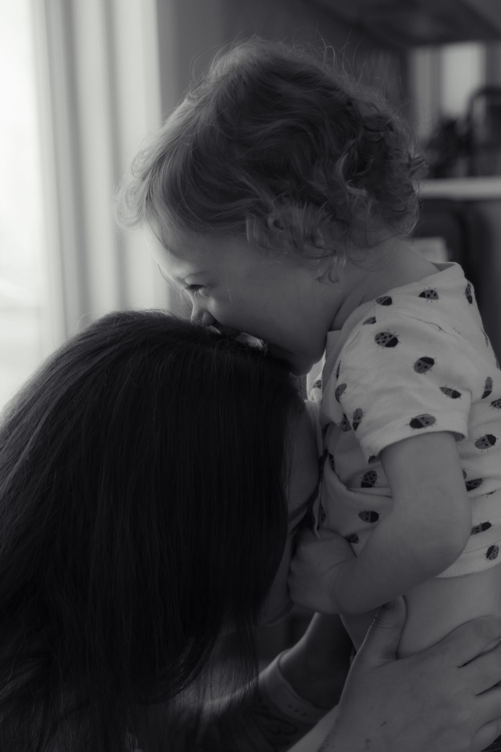 Black and white image of a mother tenderly holding her baby close, sharing a gentle moment.
