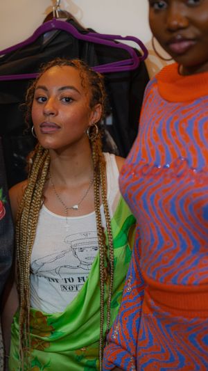 Casual behind-the-scenes shot with graphic tee and neon orange and green styling.